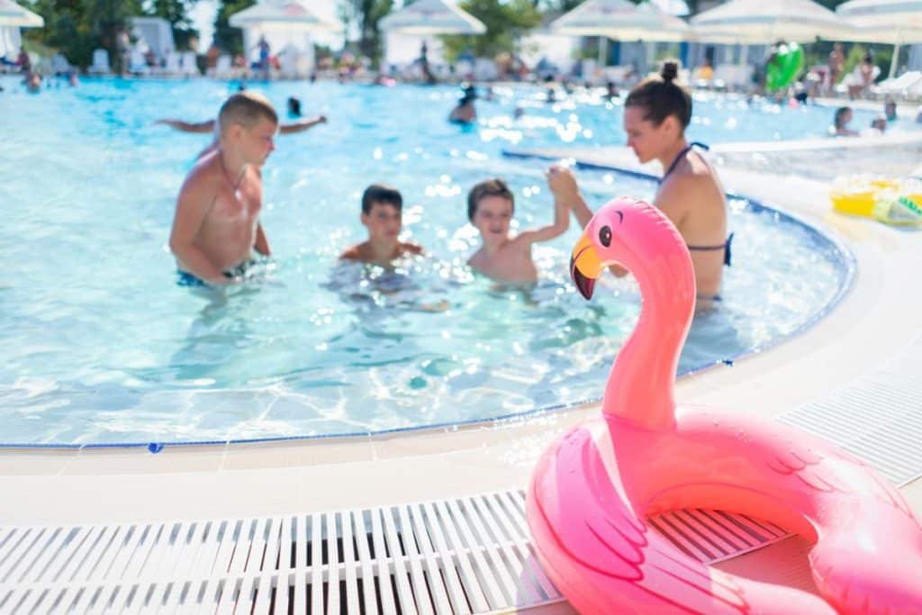 famille à la piscine avec une bouée flamand rose